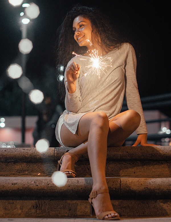 woman sitting on concrete stairs holding sparkler